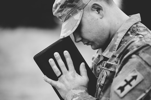 disparo escala grises joven soldado rezando mientras sostiene biblia 181624 19768